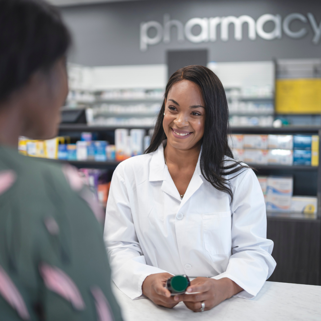 A friendly pharmacist talking with a patient about heart health and statin facts inside a bright community pharmacy.